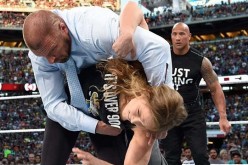 Ronda Rousey executes a Judo throw to Triple H as The Rock looks on at WrestleMania 31 last year. 