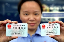 A police officer in Shanghai shows two identification cards issued to nonlocal residents in the city.