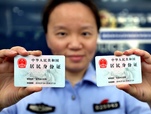 A police officer in Shanghai shows two identification cards issued to nonlocal residents in the city.