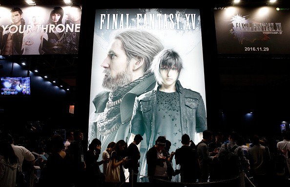 Visitors wait in line in front of an advertisement of the Final Fantasy XV video game at the Tokyo Game Show 2016 on September 15, 2016 in Chiba, Japan.