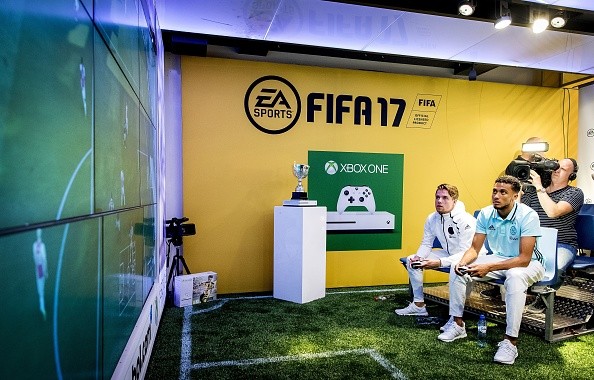 Ajax Amsterdam players Koen Weijland (L) and Jairo Riedewald play a game on an 'Xbox One' during the opening of the FIFA 17 Xperience in Amsterdam on September 22, 2016. 