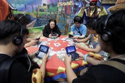 Attendees play video games on Nintendo Co.'s New 3DS LL in the Capcom Co. booth at the Tokyo Game Show 2016 at Makuhari Messe in Chiba, Japan, on Thursday, Sept. 15, 2016.