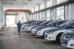 A man walks past a fleet of BYD Co. electric taxis in a charging station in Taiyuan, Shanxi Province.