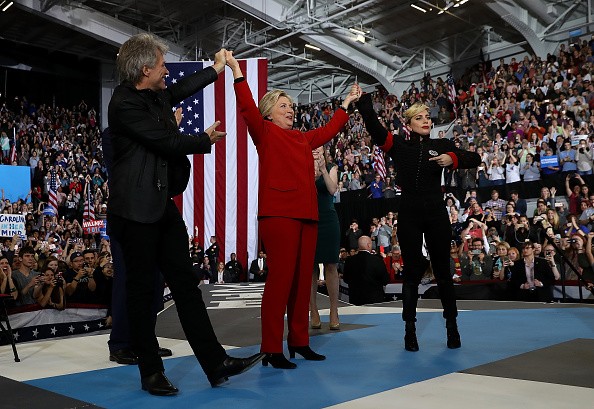 Democratic presidential nominee Hillary Clinton (C) raises her arms with musicians Jon Bon Jovi (L) and Lady Gaga during a campaign rally at North Carolina State University on November 8, 2016 in Raleigh North Carolina. 