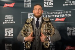 UFC two-division champion Conor McGregor holds both his belts during a press conference for UFC 205.