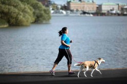 A woman runs with a dog on leash. 