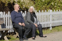 Retired senior couple seated in garden chairs appear relaxed looking out