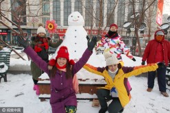 Visitors to Harbin pose for a photo with a snowman.