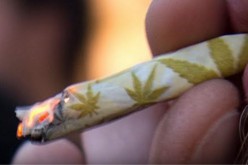 A hand-rolled marijuana cigarette with design is being smoked by a cannabis user.