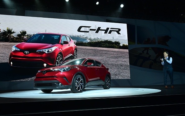 New Toyota C-HR  SUV on the display for introduction as a senior staff member takes a look at it cheerfully