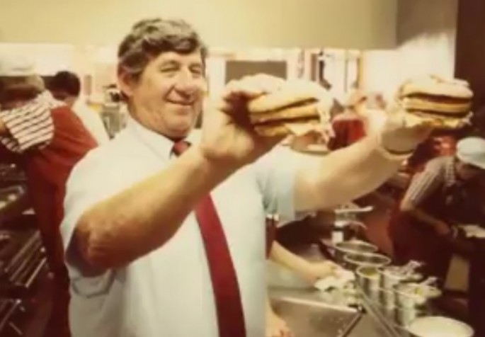 Michael “Jim” Delligatti, Creator of McDonald’s Iconic Big Mac, holding his masterpiece with both hands.