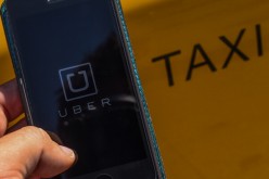 The smart phone app Uber logo is displayed on a mobile phone next to a taxi on July 1, 2014 in Barcelona, Spain. 