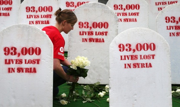 A social worker places roses among rows of gravestones symbolizing the 93,00 people killed in Syria, on June 17, 2013, in Belfast, Northern Ireland.