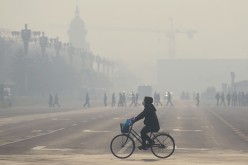  A woman wears a mask as she rides her bicycle along a street near Tiananmen Square on the third day of a red alert for pollution in Beijing.