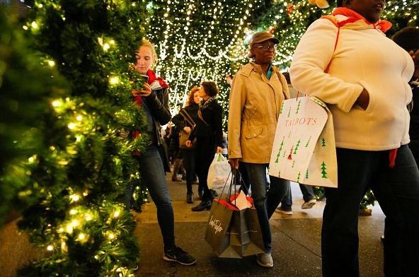 People carry retail shopping bags through holiday decorations during Black Friday events on November 25, 2016 in New York City. 
