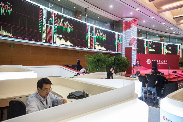 A man monitors stock changes on the electronic boards at the Shanghai Stock Exchange.