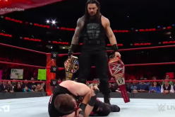 Roman Reigns looks at Kevin Owens while holding both the U.S. and Universal Titles. 