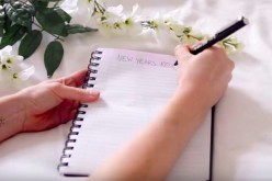 An individual is starting to write her New Year's resolution for 2017 on her notebook. 