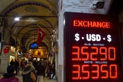 People walk past a sign showing the exchange rate for the U.S. dollar.