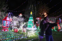 Visitors pose for a selfie as they view the Cambage Court Christmas Lights in the suburb of Davidson after the residents decorated their home and open the yard to visitors in celebration of Christmas.