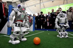 Robots powered by artificial intelligence play a football game at a technology convention.