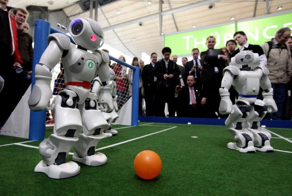 Robots powered by artificial intelligence play a football game at a technology convention.