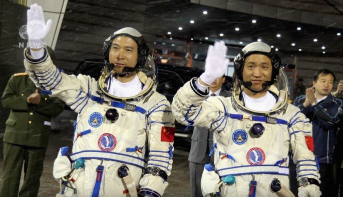 Chinese astronauts Fei Junlong (L) and Nie Haisheng wave before boarding the Shenzhou VI spacecraft at Jiuquan Satellite Launch Center on October 12, 2005 in Jiuquan of Gansu Province, northwest China