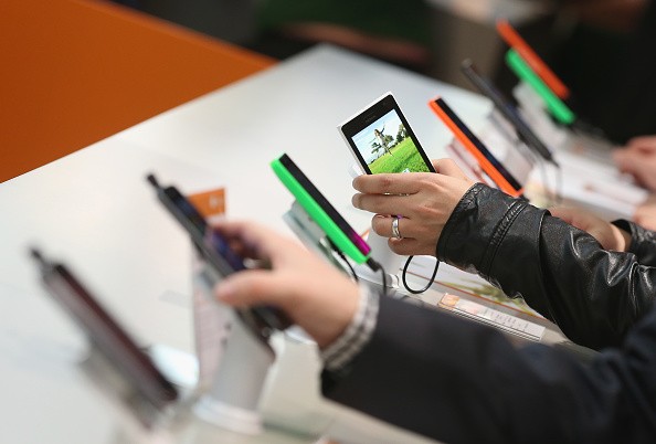 Visitors look at Windows-enabled smartphones, including the Nokia Lumia series, at the Microsoft stand the 2015 CeBIT.