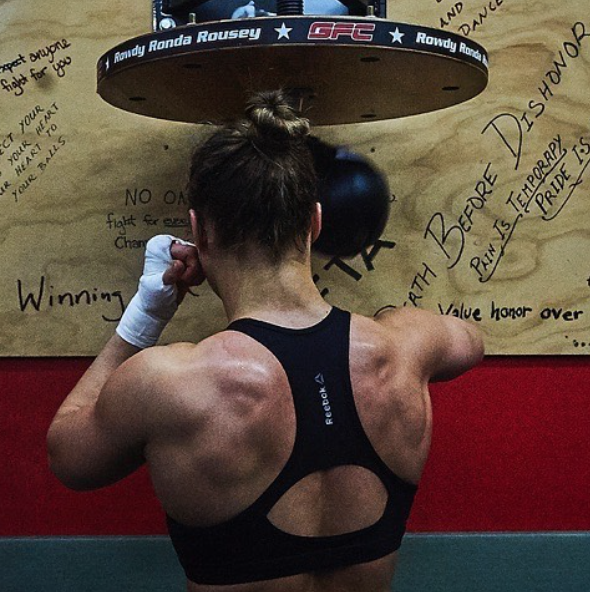 Ronda Rousey shows off her physique by posing in front of a speed bag at the gym she trains in. 