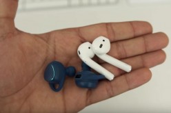 Apple AirPods and Samsung Gear IconX are placed on the palm for viewing and comparison. 
