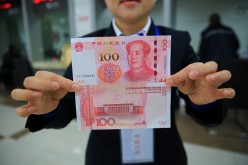 A bank staff shows the 100 yuan bill with new counterfeit features.