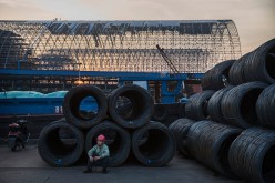 A worker takes a break as steel wire waits to be loaded onto barges in Changzhou, Jiangsu Province, on May 12, 2016.