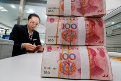 A staff counts renminbi notes at a bank in Lianyungang, Jiangsu Province.