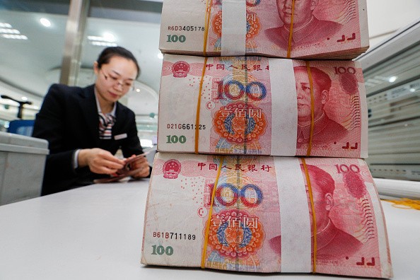 A staff counts renminbi notes at a bank in Lianyungang, Jiangsu Province.