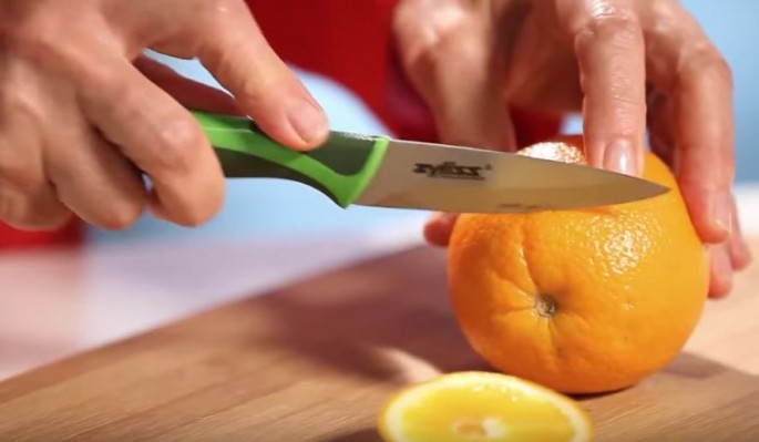 An orange, which is a good source of vitamin C, is being sliced and prepared for eating.