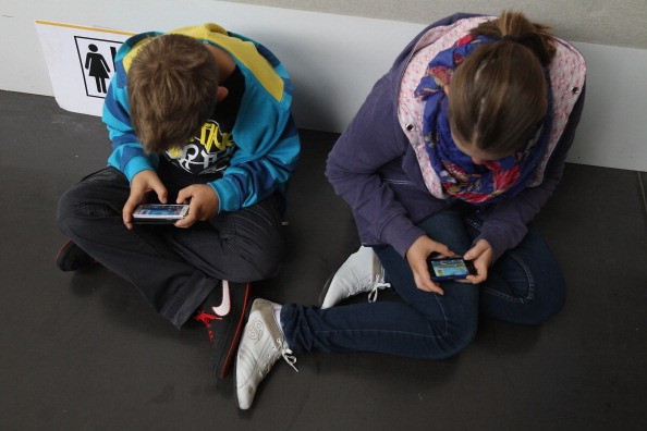  Children play video games on smartphones while attending a public event 
