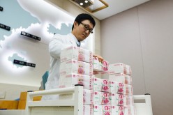 An employee piles bundles of yuan notes in an offshore bank.