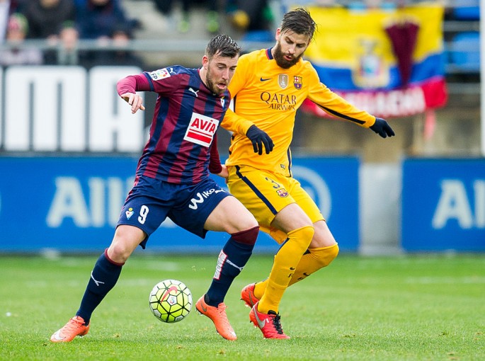 Eibar forward Sergi Enrich (L) competes for the ball against Barcelona's Gerard Pique.