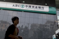 A man walks past the Agricultural Bank of China Ltd., the nation's third-largest lender by market value, as government cracks down on lending to curb loan expansion.