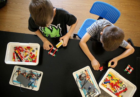 Children learn coding skills while constructing a Lego robotic alligator during a sports/coding summer camp.
