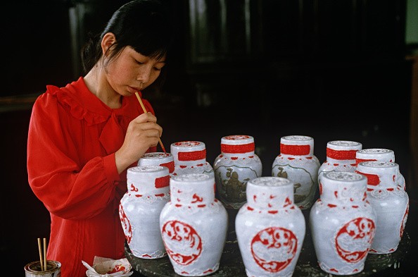 A woman handpaints jars of rice wine in a rice wine factory in Shaoxing. 