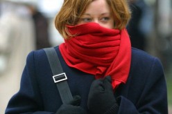 A woman with her scarf wrapped around her nose and mouth, feeling cold