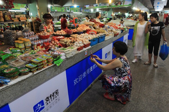 A woman scans the QR code by cellphone to pay for her purchases at a market in Wenzhou, east China's Zhejiang Province.