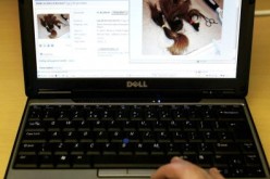A man uses a laptop displaying a page on its screen of the online auction site Ebay