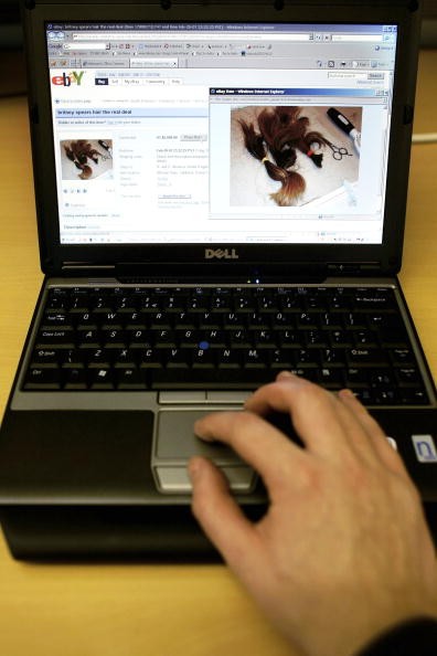 A man uses a laptop displaying a page on its screen of the online auction site Ebay