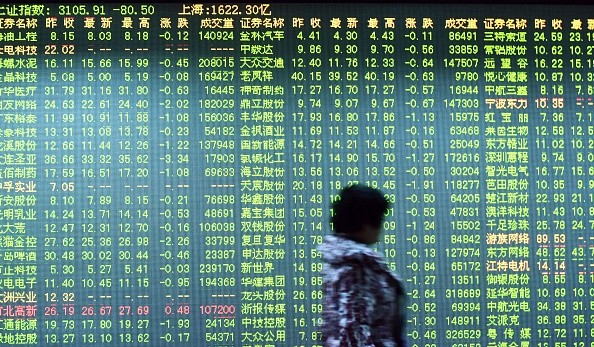 An investor walks past a screen showing stock market movements at a securities firm in Hangzhou.