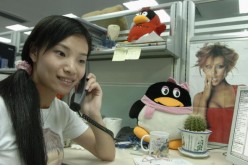 A worker makes a phone call beside an emblem of Tencent QQ instant messaging service, in the headquarters office of the Tencent Holdings Limited in Shenzhen.