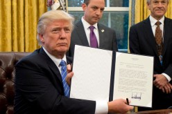 U.S. President Donald Trump shows the Executive Order withdrawing the U.S. from the Trans-Pacific Partnership (TPP) after signing it in the Oval Office of the White House on Monday, Jan. 23, 2017. 