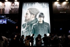 Visitors wait in line in front of an advertisement of the Final Fantasy XV video game at the Tokyo Game Show 2016 on September 15, 2016 in Chiba, Japan.