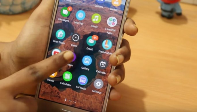 A Samsung Z3 phone is being held by a hand as it showcase its Tizen OS.